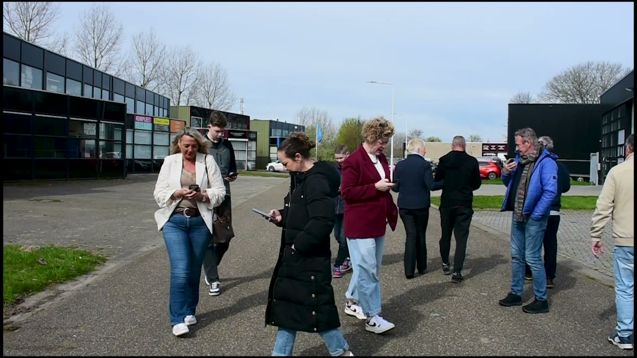 Bezoekers kijken op hun telefoon tijdens een wandeling over een bedrijventerrein