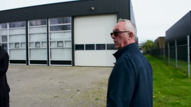 Man met zonnebril bij een bedrijfspand
